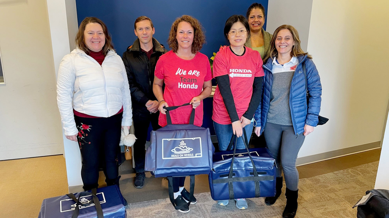 A group of Honda employees pose doing charitable work. 