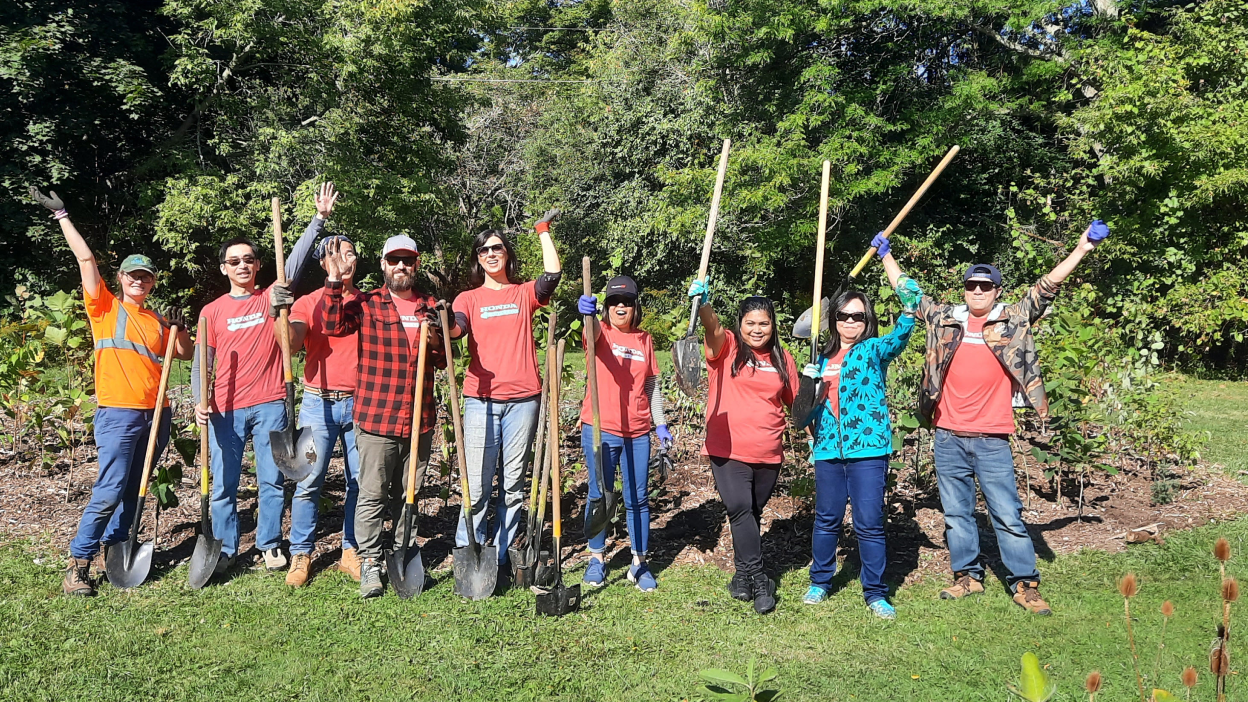 A group of Honda employees pose while planting trees. 