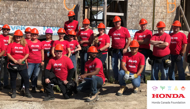 A group of Honda employees wearing "Team Honda" shirts pose. 