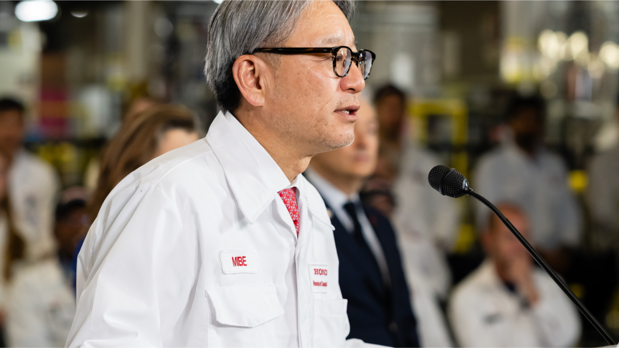 A male Honda staff member is speaking in a mic to a group.