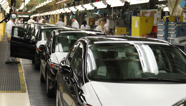 A line of Honda cars in a factory being checked and tested by employees.