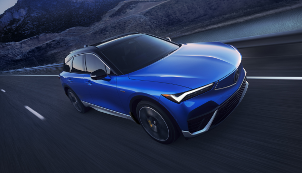 A blue Acura drives on an open road. 