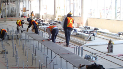 Workers are shown installing a heated floor system at Honda headquarters. 