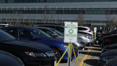 Employee vehicles are depicted in the parking lot at Honda headquarters. 