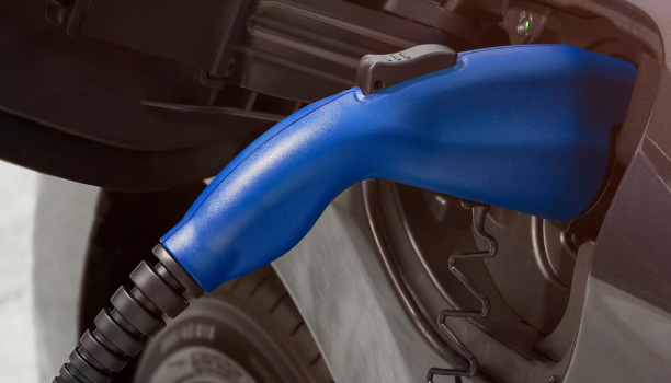 A close-up of a fuel nozzle in the gas tank of a blue Honda vehicle is shown. 