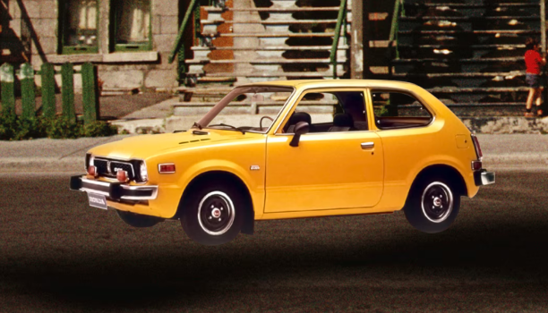 An original yellow Honda vehicle from 1969 is parked outside townhouses. 
