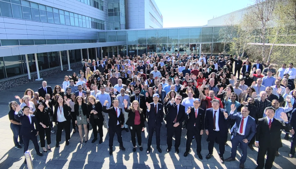 A large group of Honda employees pose together outside Honda headquarters.