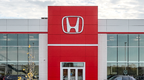 The exterior of a Honda dealership with the Honda logo is depicted. 