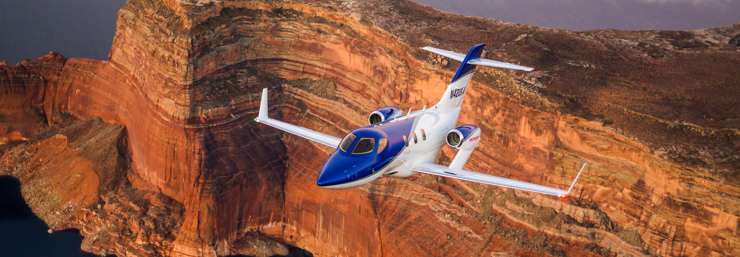 A Honda Jet is pictured from above soaring over a canyon,.