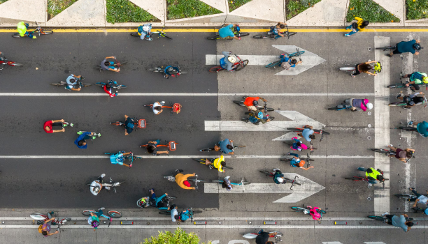 An overhead shot depicts a group of cyclists on a city street.