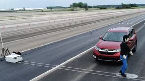 A still image from a video depicts a pedestrian crossing in front of a Honda vehicle. 